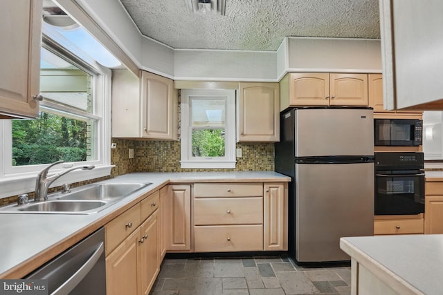kitchen featuring a sink, stone tile flooring, black appliances, light countertops, and light brown cabinetry