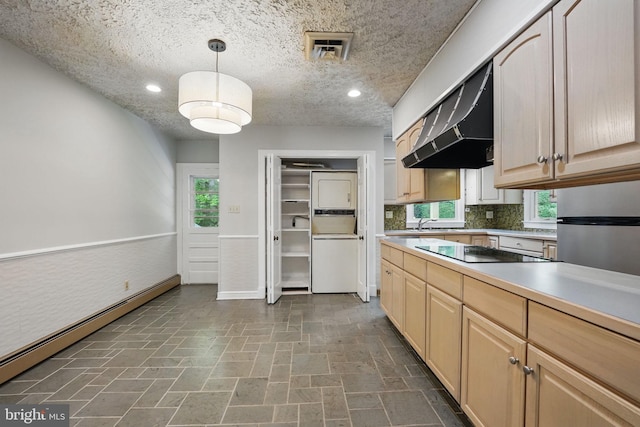 kitchen with stacked washer and clothes dryer, under cabinet range hood, visible vents, baseboard heating, and black electric cooktop