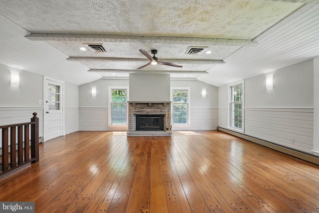 unfurnished living room with a wainscoted wall, visible vents, lofted ceiling, and wood-type flooring
