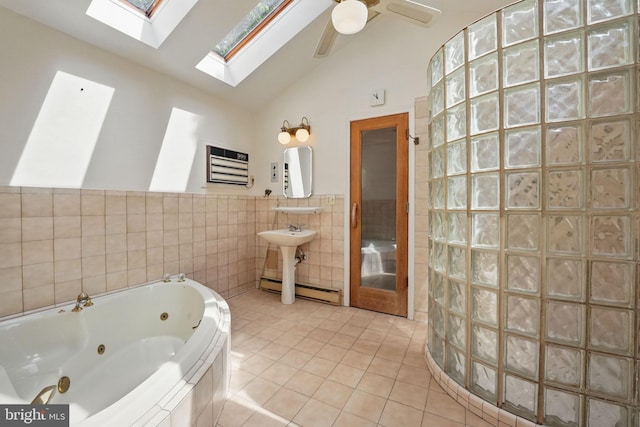 bathroom featuring tile walls, a baseboard heating unit, tile patterned floors, a whirlpool tub, and lofted ceiling with skylight