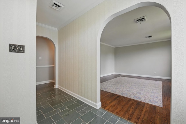 hallway featuring ornamental molding, visible vents, baseboards, and arched walkways