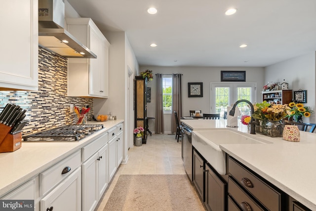 kitchen with wall chimney exhaust hood, appliances with stainless steel finishes, tasteful backsplash, white cabinets, and recessed lighting
