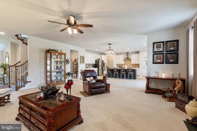 living room with light colored carpet, stairs, recessed lighting, a ceiling fan, and a chandelier