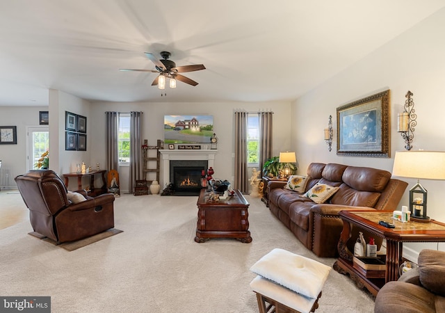living area featuring healthy amount of natural light, a ceiling fan, light carpet, and a high end fireplace