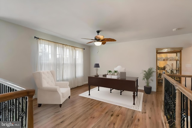 home office with light wood finished floors, ceiling fan, and baseboards