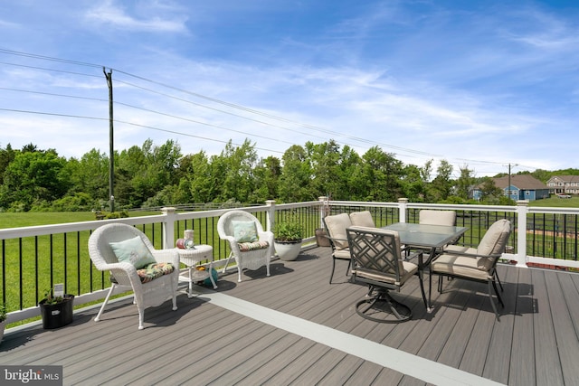 wooden terrace featuring outdoor dining area and a yard