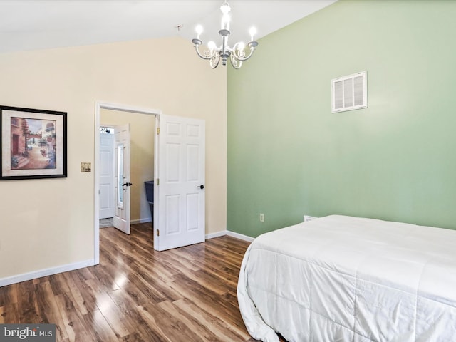 bedroom featuring a chandelier, baseboards, lofted ceiling, and wood finished floors