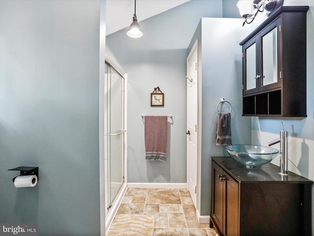 full bathroom featuring a shower stall, baseboards, stone finish floors, and vanity