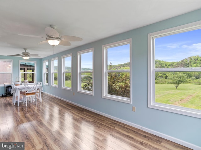 sunroom / solarium featuring baseboards, wood finished floors, and a wooden deck