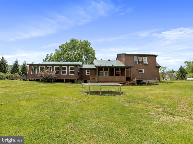 back of house with a yard, metal roof, and a trampoline