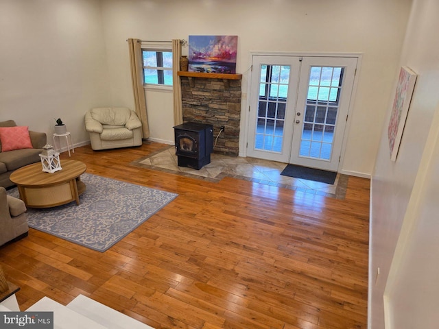 living room with french doors, wood-type flooring, baseboards, and a wood stove
