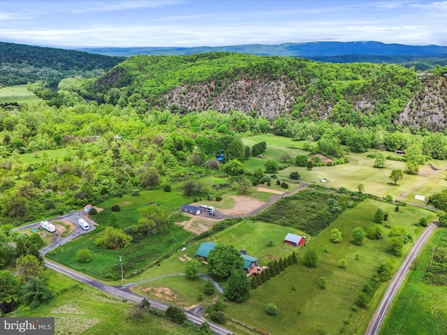 aerial view of property and surrounding area featuring a heavily wooded area and mountains