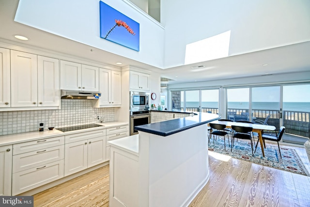 kitchen featuring stainless steel appliances, light wood-style flooring, white cabinets, under cabinet range hood, and recessed lighting