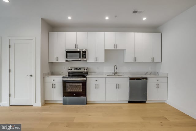 4902 D St SE, Washington, DC 20019 - kitchen with stainless steel appliances, a sink, white cabinets, baseboards, and recessed lighting