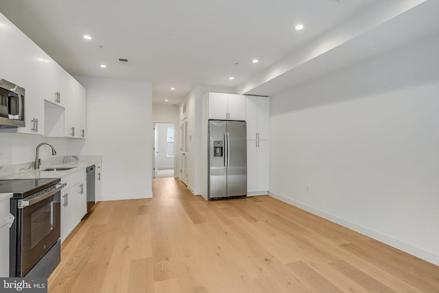 4902 D St SE, Washington, DC 20019 - kitchen featuring stainless steel appliances, a sink, light wood-type flooring, white cabinets, and recessed lighting