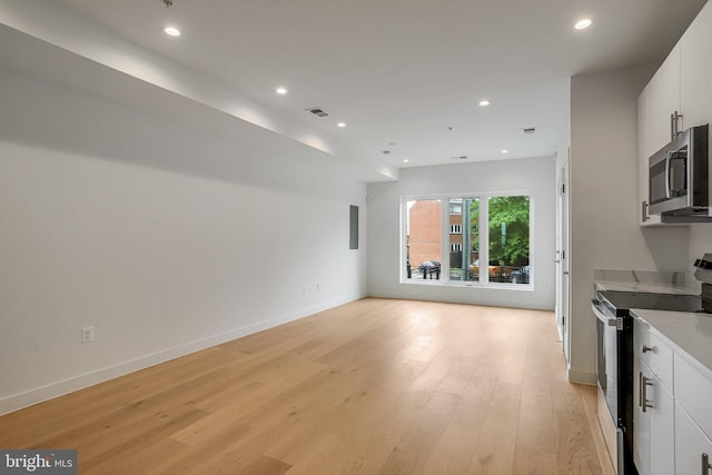 4902 D St SE, Washington, DC 20019 - kitchen featuring electric range oven, stainless steel microwave, open floor plan, light wood-style flooring, and recessed lighting