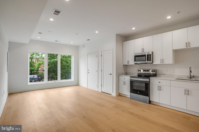 4902 D St SE, Washington, DC 20019 - kitchen with stainless steel appliances, a sink, light wood-type flooring, recessed lighting, and white cabinets