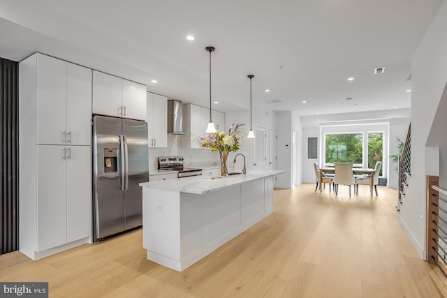 4902 D St SE, Washington, DC 20019 - kitchen with stainless steel appliances, wall chimney exhaust hood, light wood-style floors, a sink, and white cabinetry