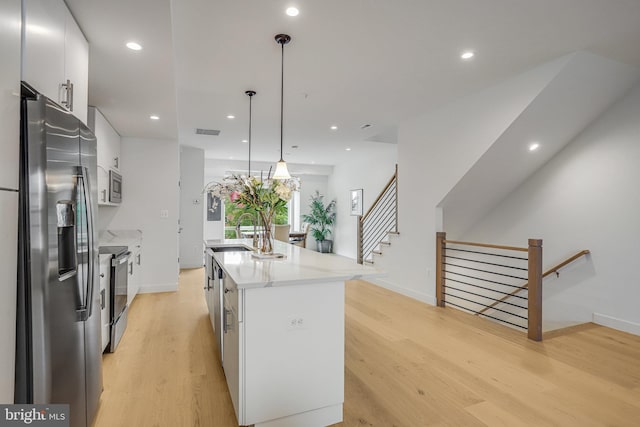 4902 D St SE, Washington, DC 20019 - kitchen featuring appliances with stainless steel finishes, light wood-style floors, a center island with sink, light countertops, and baseboards