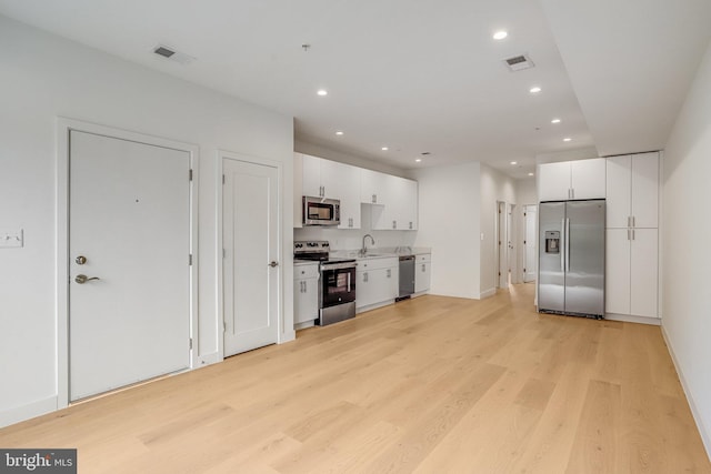 4902 D St SE, Washington, DC 20019 - kitchen with appliances with stainless steel finishes, light wood-style flooring, white cabinetry, a sink, and recessed lighting