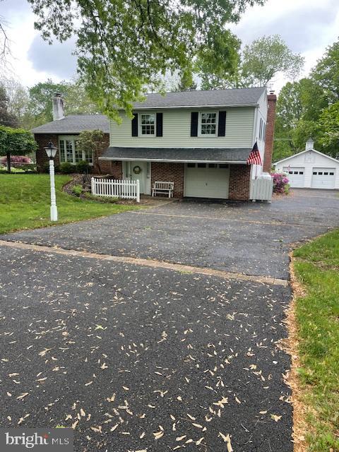 view of front of home with a chimney, brick siding, a front lawn, and a garage