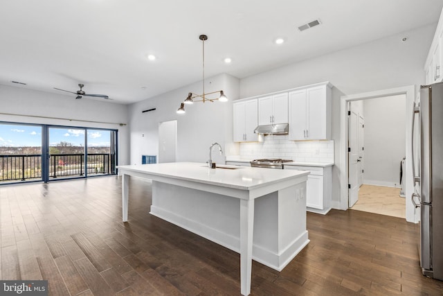 44691 Wellfleet Dr Unit 508, Ashburn, VA 20147 - kitchen with under cabinet range hood, dark wood-style floors, tasteful backsplash, freestanding refrigerator, and light countertops