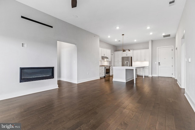 44691 Wellfleet Dr Unit 508, Ashburn, VA 20147 - unfurnished living room featuring recessed lighting, a glass covered fireplace, dark wood-style floors, baseboards, and a sink
