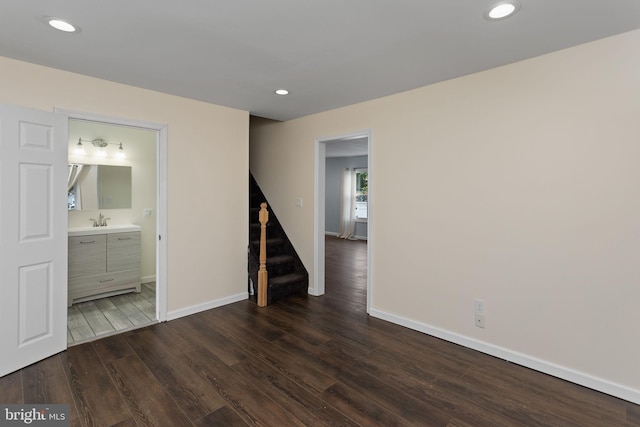 empty room featuring wood finished floors, stairs, baseboards, a sink, and recessed lighting