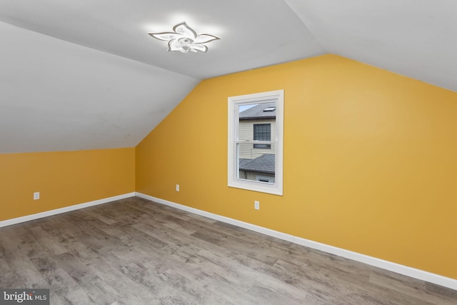 additional living space with vaulted ceiling, wood finished floors, and baseboards
