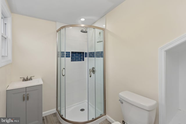 full bath with a sink, a shower stall, toilet, and baseboards