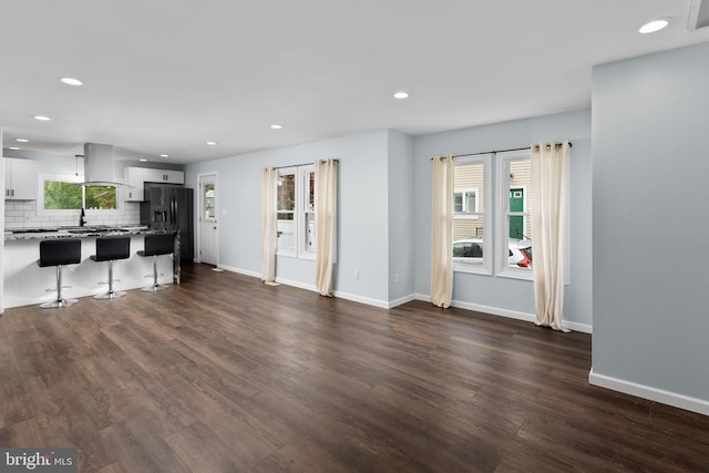 unfurnished living room with dark wood-style flooring, baseboards, and recessed lighting
