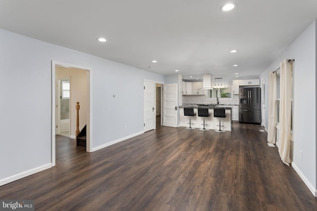 unfurnished living room featuring recessed lighting, dark wood-type flooring, and baseboards
