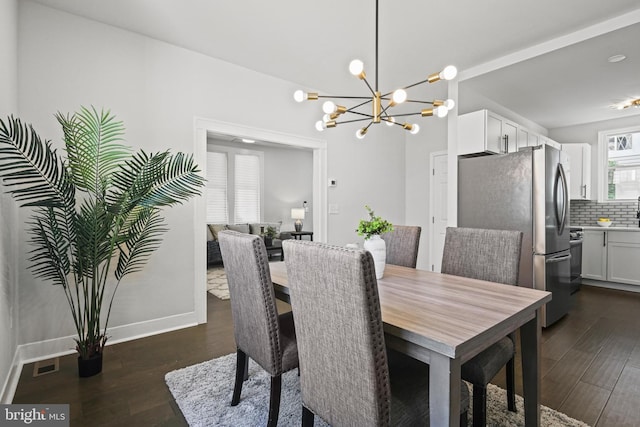 dining area featuring dark wood-style flooring, a chandelier, and baseboards