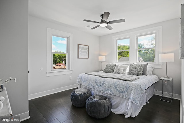 bedroom featuring multiple windows, baseboards, dark wood-type flooring, and a ceiling fan