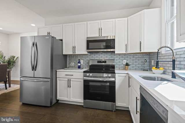 kitchen featuring appliances with stainless steel finishes, a sink, recessed lighting, white cabinetry, and backsplash