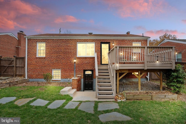 304 Moncure Dr, Alexandria, VA 22314 - back of property at dusk with a lawn, brick siding, fence, stairs, and a deck