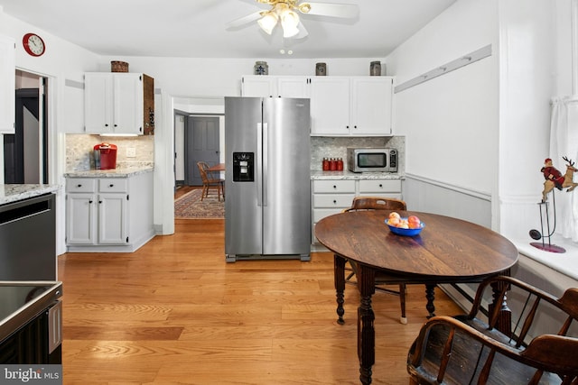 kitchen featuring stainless steel appliances, decorative backsplash, a ceiling fan, and white cabinets
