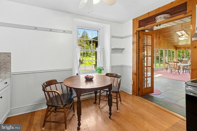 dining room featuring a wainscoted wall, a wealth of natural light, wood finished floors, and a ceiling fan