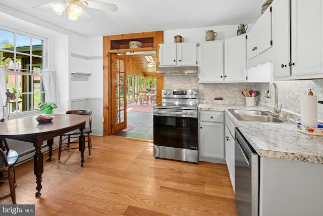 kitchen featuring a sink, stainless steel appliances, ceiling fan, under cabinet range hood, and light countertops