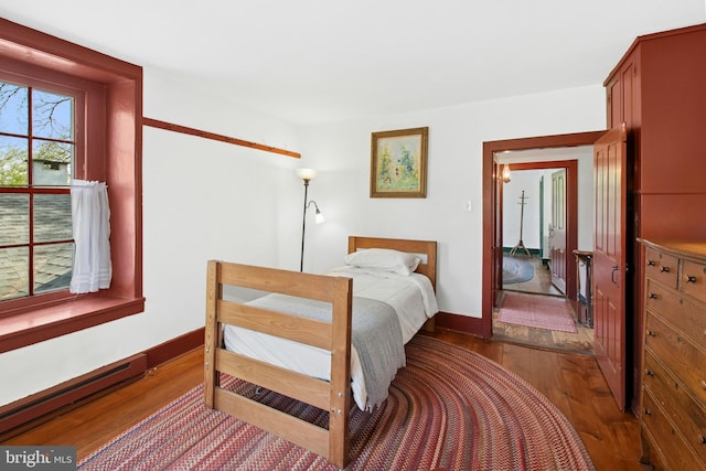 bedroom with baseboards, baseboard heating, and dark wood finished floors