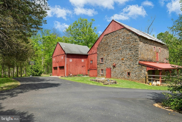 view of side of property featuring stone siding, an outbuilding, a barn, and a garage