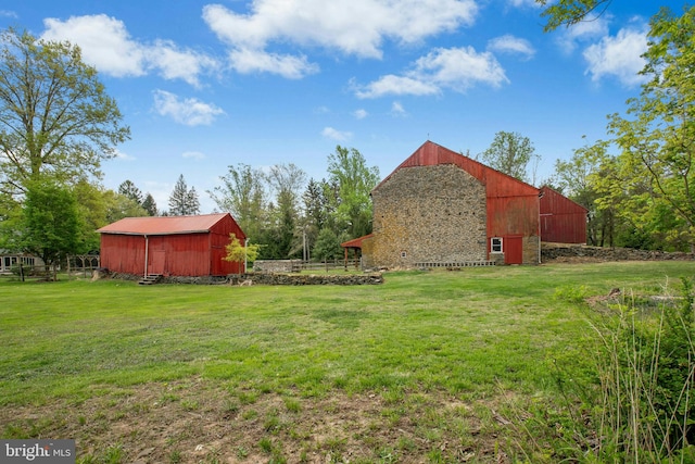 view of yard with an outdoor structure, an outbuilding, fence, and a barn