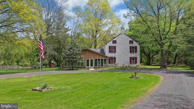 view of front of home featuring a front yard, a sunroom, curved driveway, and fence