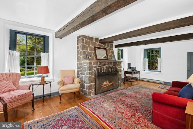 living room featuring a baseboard radiator, wood-type flooring, beamed ceiling, and a stone fireplace