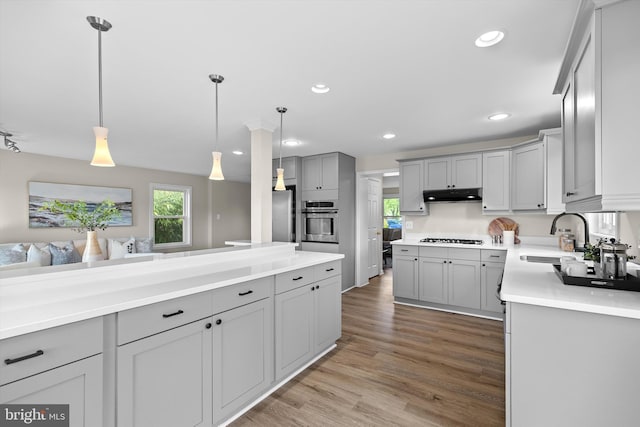 kitchen with a sink, gray cabinetry, oven, under cabinet range hood, and gas stovetop