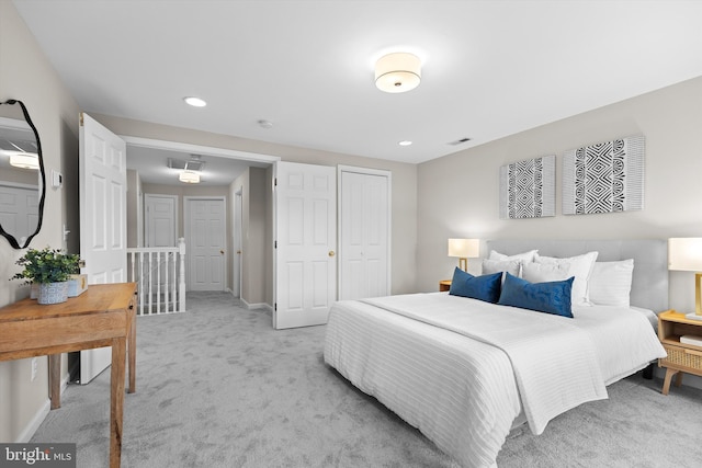 bedroom with light colored carpet, recessed lighting, baseboards, and a closet