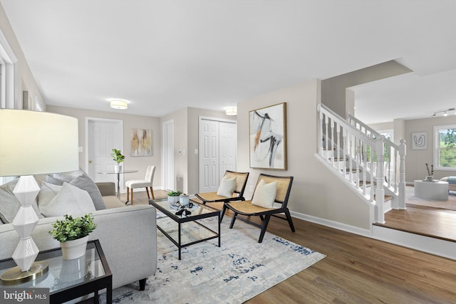 living area with stairs, wood finished floors, and baseboards