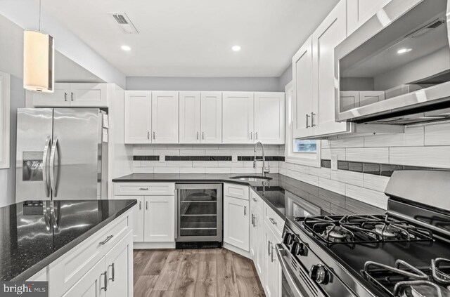 22 Duncan Ave, Westville, NJ 08093 - kitchen featuring appliances with stainless steel finishes, beverage cooler, a sink, white cabinets, and tasteful backsplash