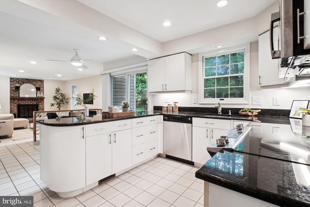 kitchen featuring appliances with stainless steel finishes, a peninsula, a fireplace, open floor plan, and a sink
