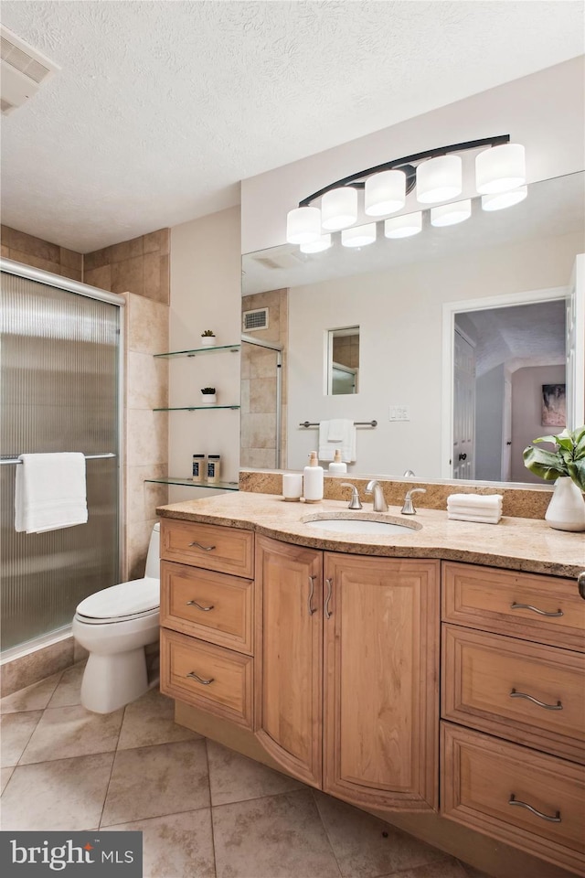full bathroom featuring a shower stall, vanity, tile patterned floors, toilet, and a textured ceiling